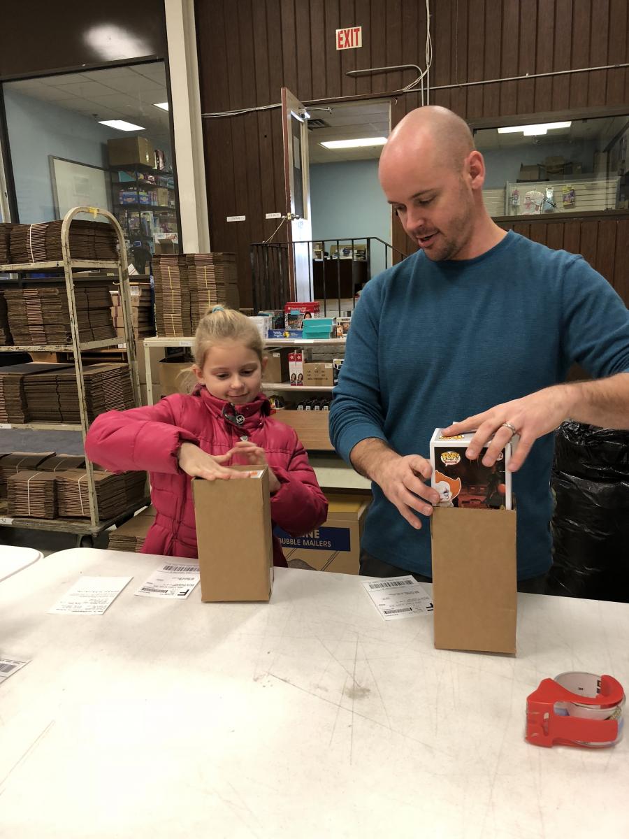 Clay Hensley, joined by his daughter Lexi, processes Christmas orders at Happen Stock Toys on Palumbo Drive.