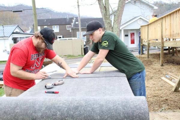 Antone Clohessy (left) and Caden Klatt (right) with YouthGo in Neenah, Wis. cut tar paper to apply to a handicap accessible ramp to prevent falls.